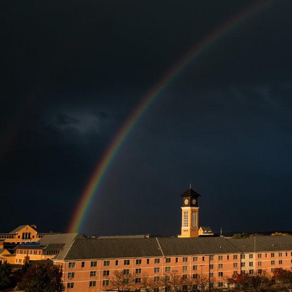 在一所大学校园前，一道彩虹映衬着乌云密布的天空