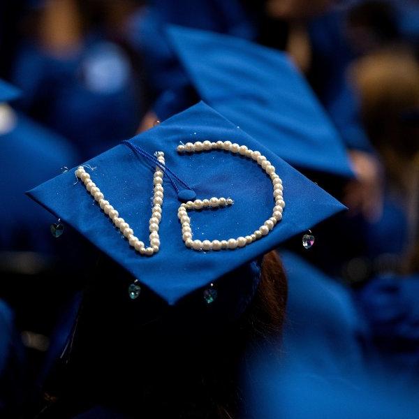 A blue mortarboard with the initials "GV" spelled out using pearls.