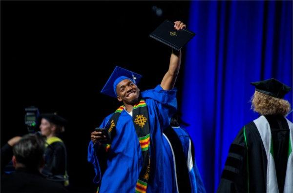 毕业典礼上，一名学生自豪地高举着他的毕业证书走过讲台.