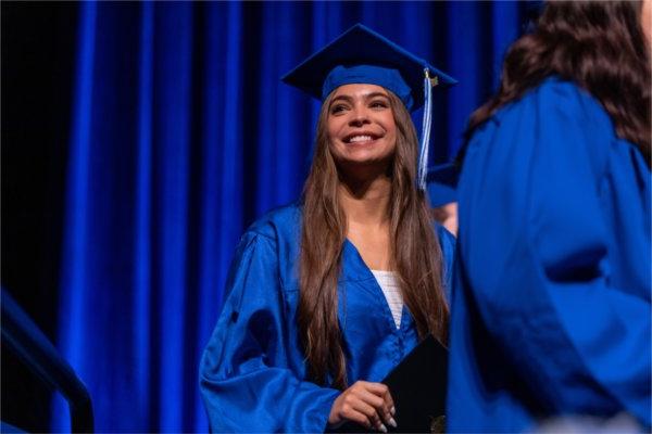 即将毕业的学生拉里萨·霍林沃斯在接受毕业证书时对着人群中的家人微笑.
