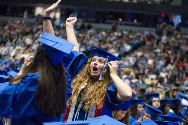  一位大学毕业生一边打手机一边挥舞着拳头大喊大叫.
