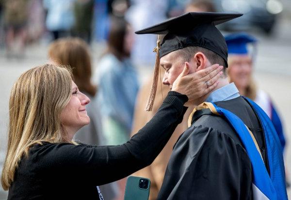  一位母亲在儿子毕业前把手放在他的脸上.
