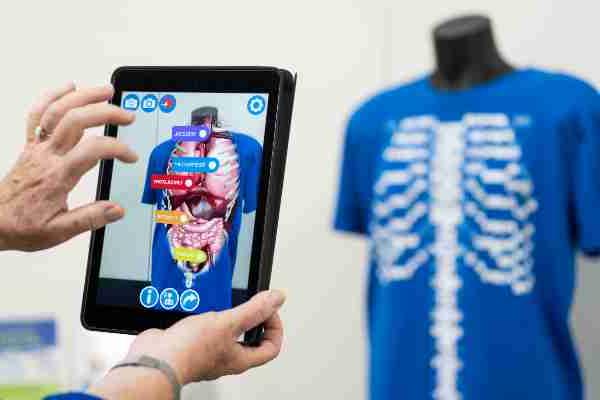 A person uses a touch screen device showing human anatomy.  